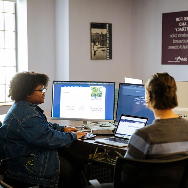 Women and gender studies major students talking and typing on a desktop computer.